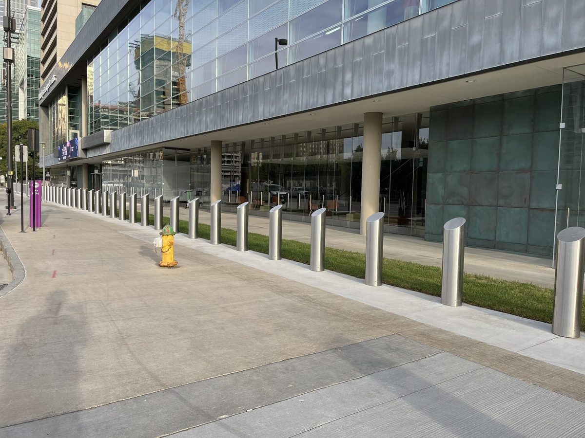 Row of brushed stainless steel dome-top bollards along the glass facade of the Omaha Performing Arts center