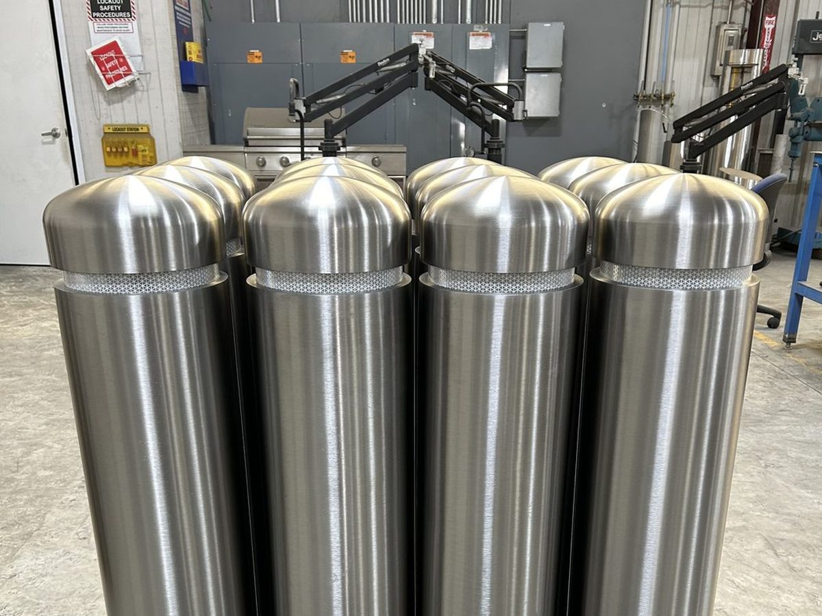 Brushed stainless steel dome-top bollard covers with a single reflective reveal band
