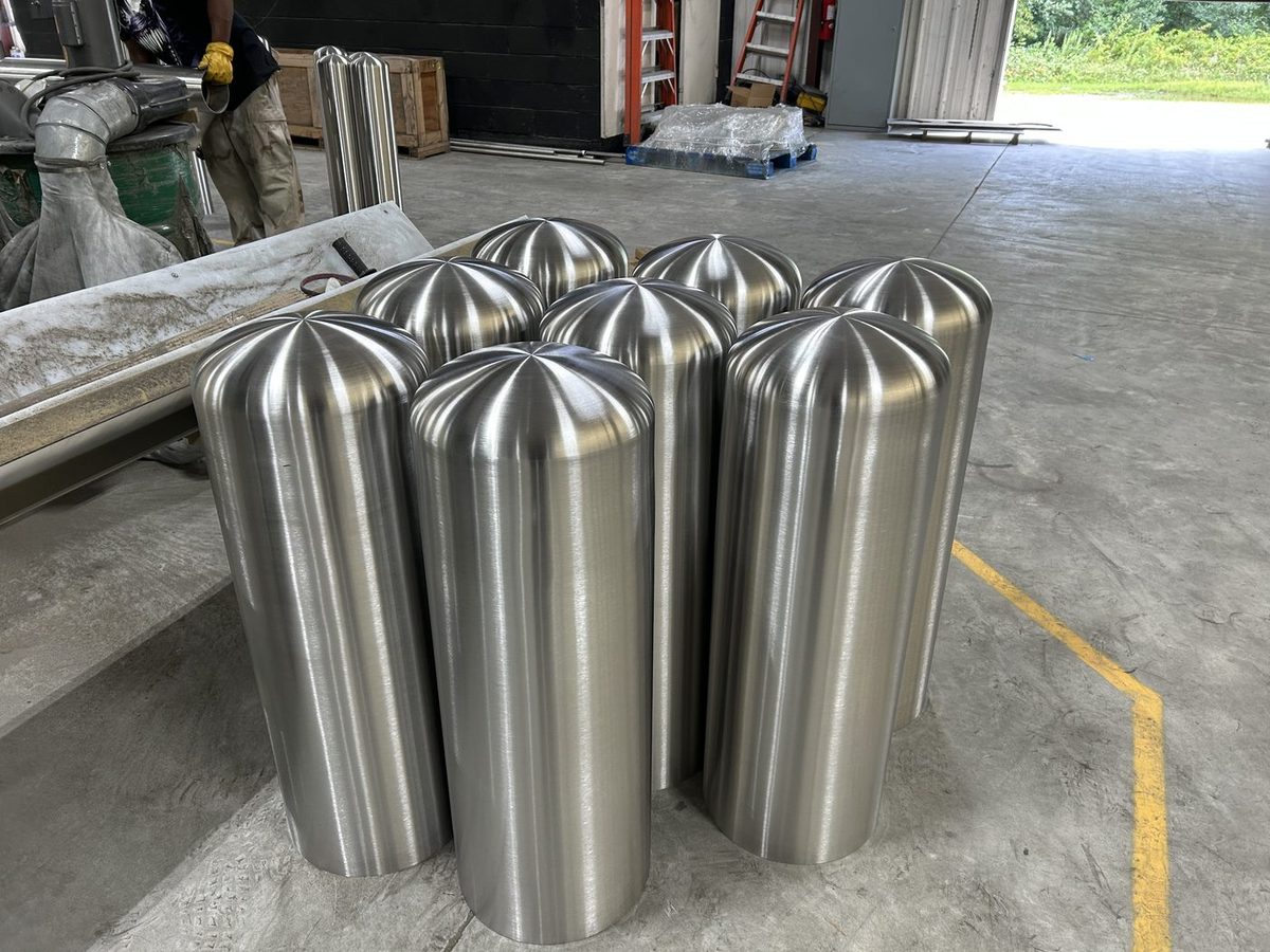 Cluster of brushed stainless steel dome-top bollard covers in the fabrication shop