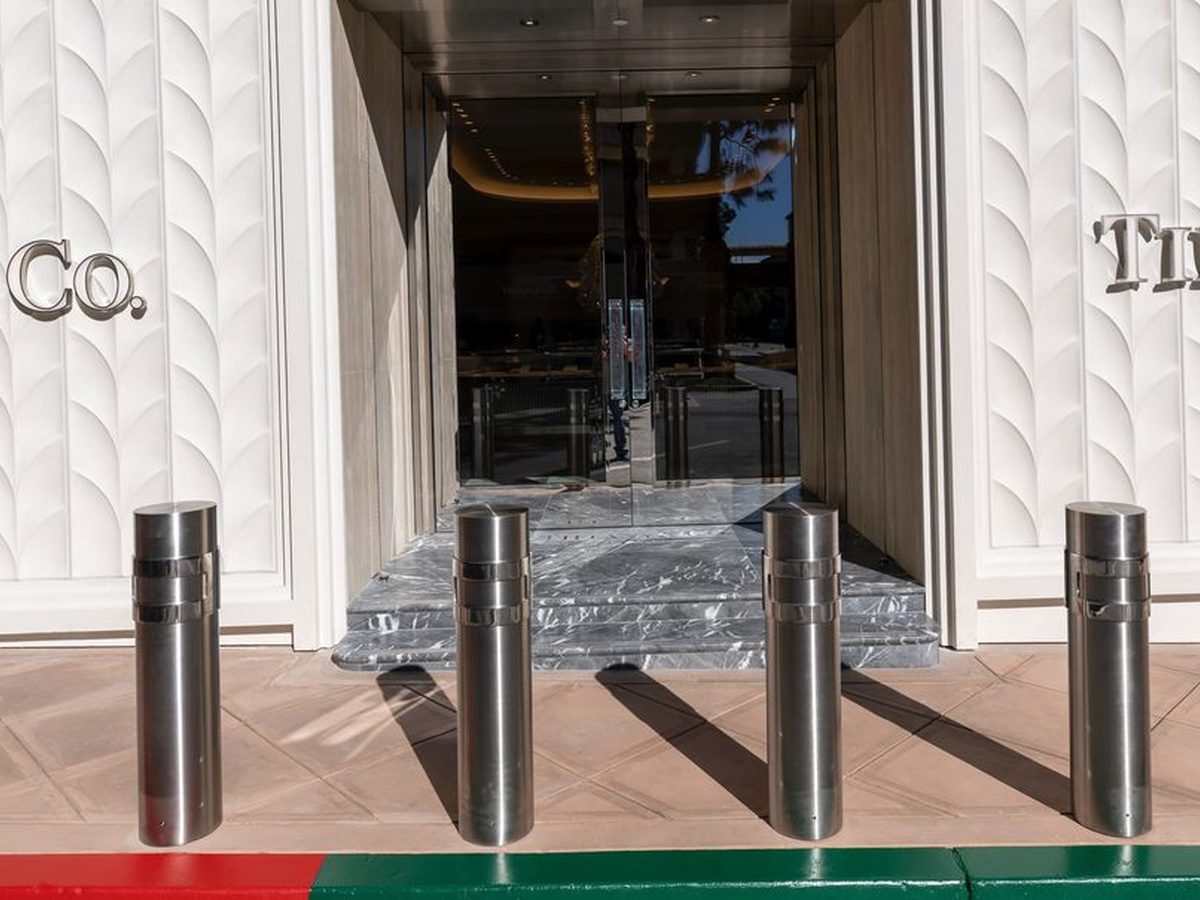 Polished stainless steel dome-top bollard covers flanking a Tiffany & Co. storefront entrance