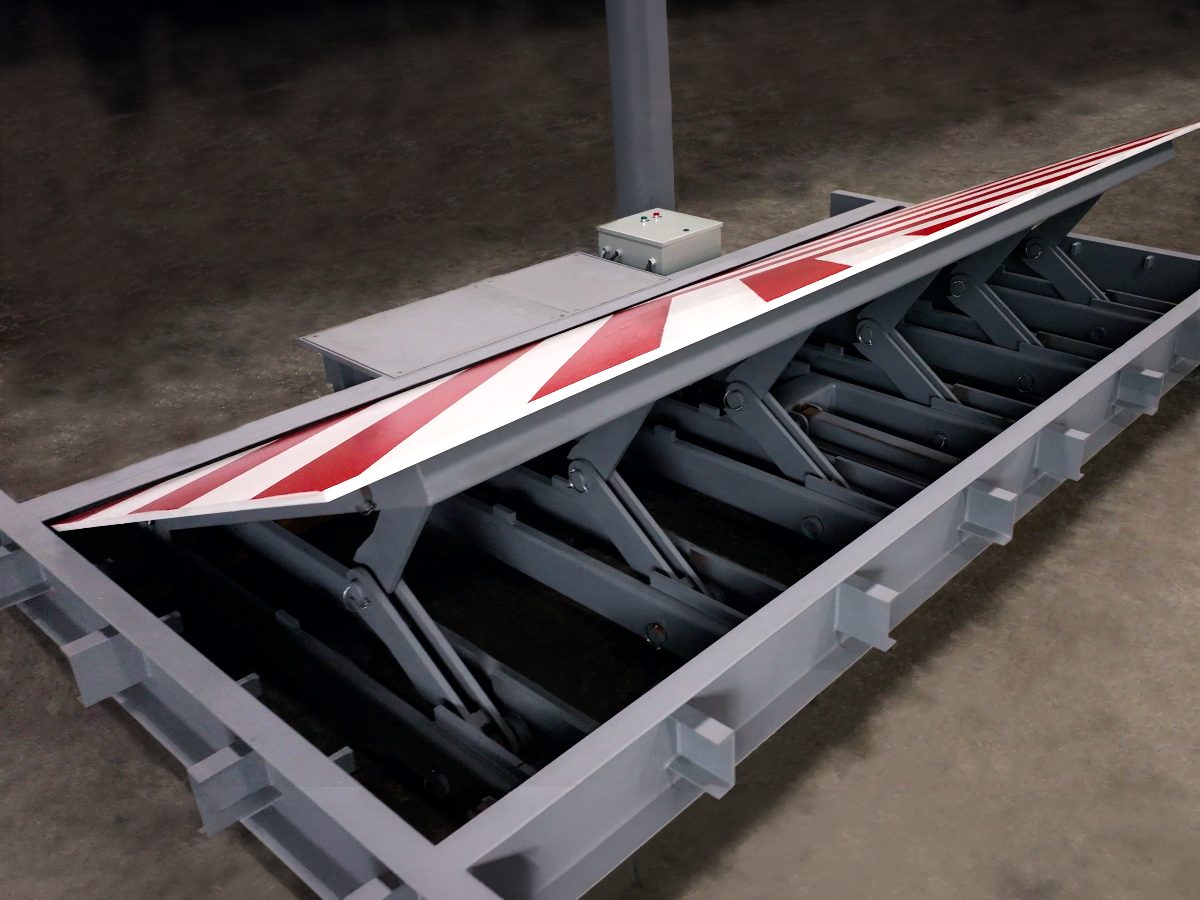 Vehicle wedge barrier raised on its scissor-lift mechanism with red and white chevron markings